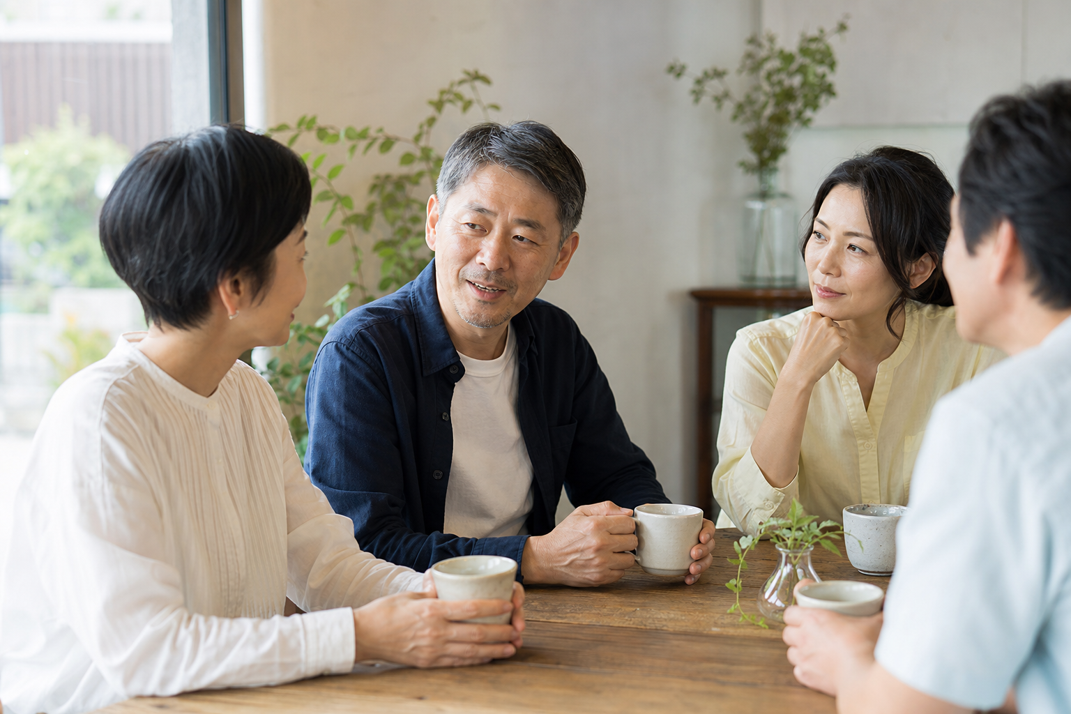 カフェのテーブルを囲み、カップを手に話している参加者